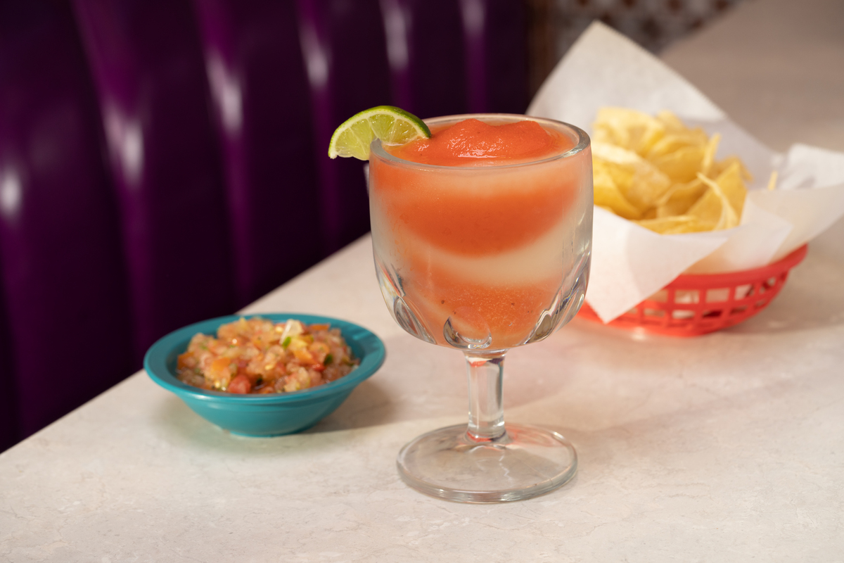 Chuy's Swirl Margarita served on a glass next to pico and a side of chips.