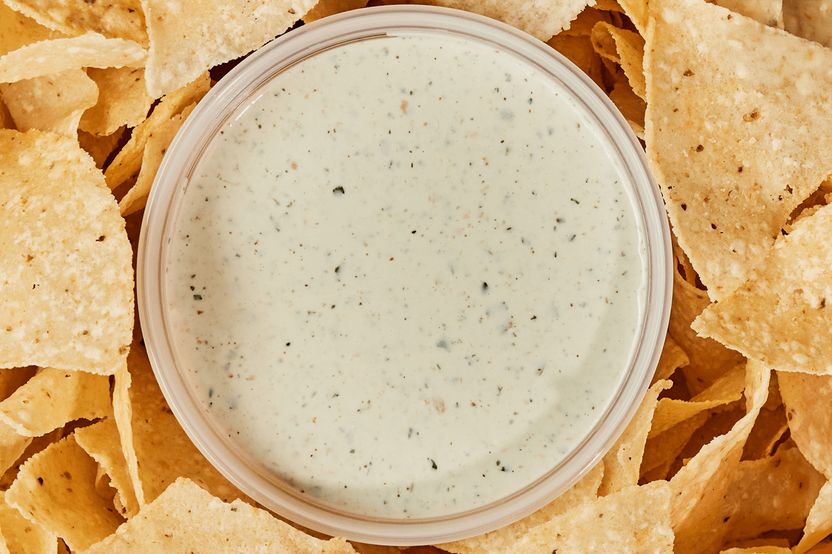Chuy's Creamy Jalapeno Dip, next to a bunch of tortilla chips.