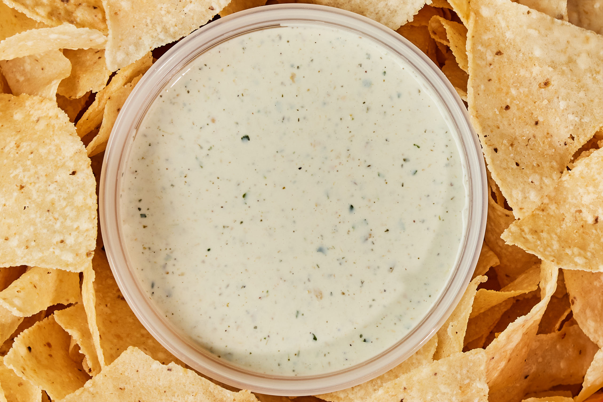 Chuy's Creamy Jalapeno Dip, next to a bunch of tortilla chips.