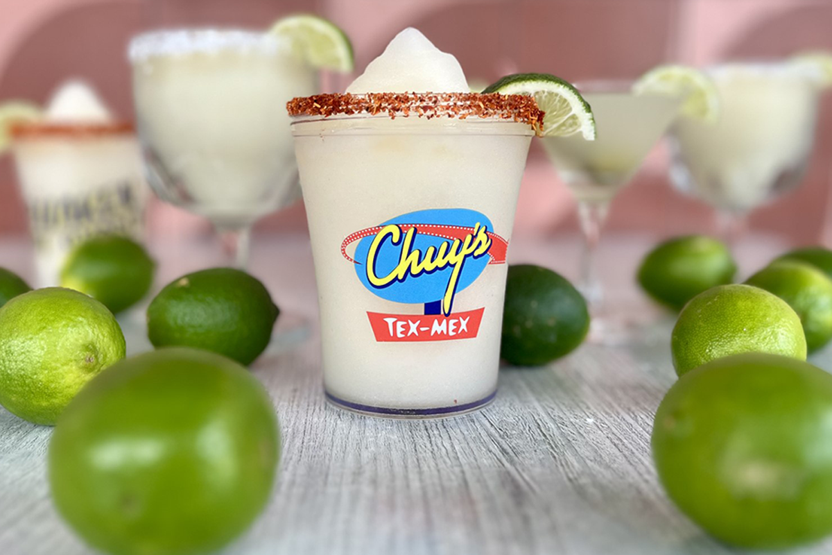 Chuy's Frozen Margarita served next to a bunch of fresh limes.