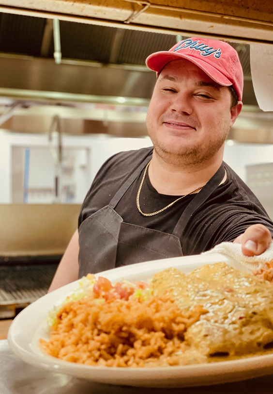 Chuy's kitchen staff member putting a dish out for the server to pickup to deliver to the customer.