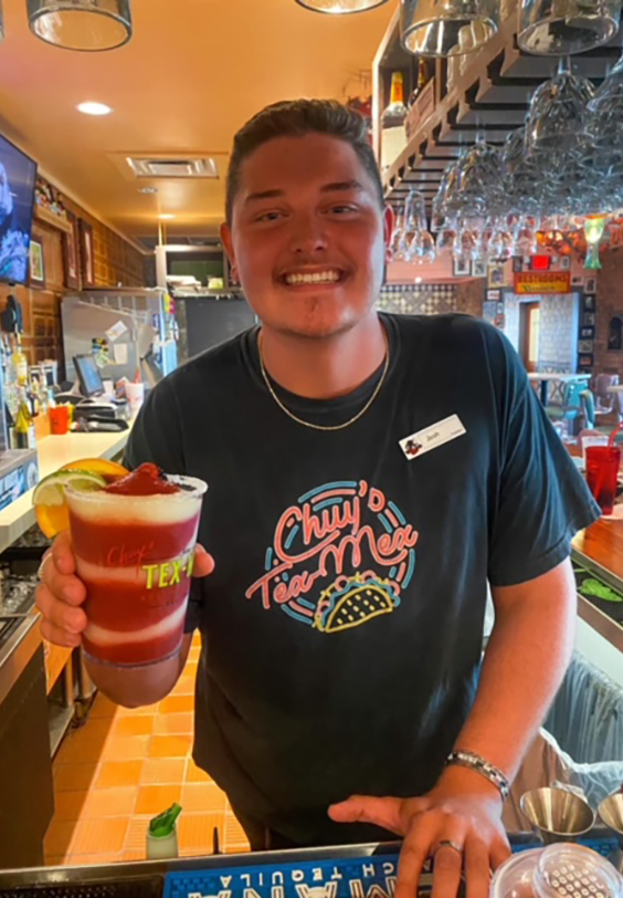 Chuy's bartender serving a Black Berry Swirl with a smile.