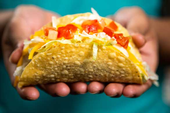 Close-up of a crispy ground beef taco with lettuce, cheese, and tomatoes, served at Chuy's during National Taco Day.