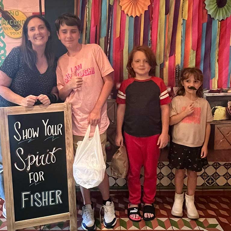 Kids and a mom at Chuy's right next to the 'Show Your Spirit For Fisher' sign.